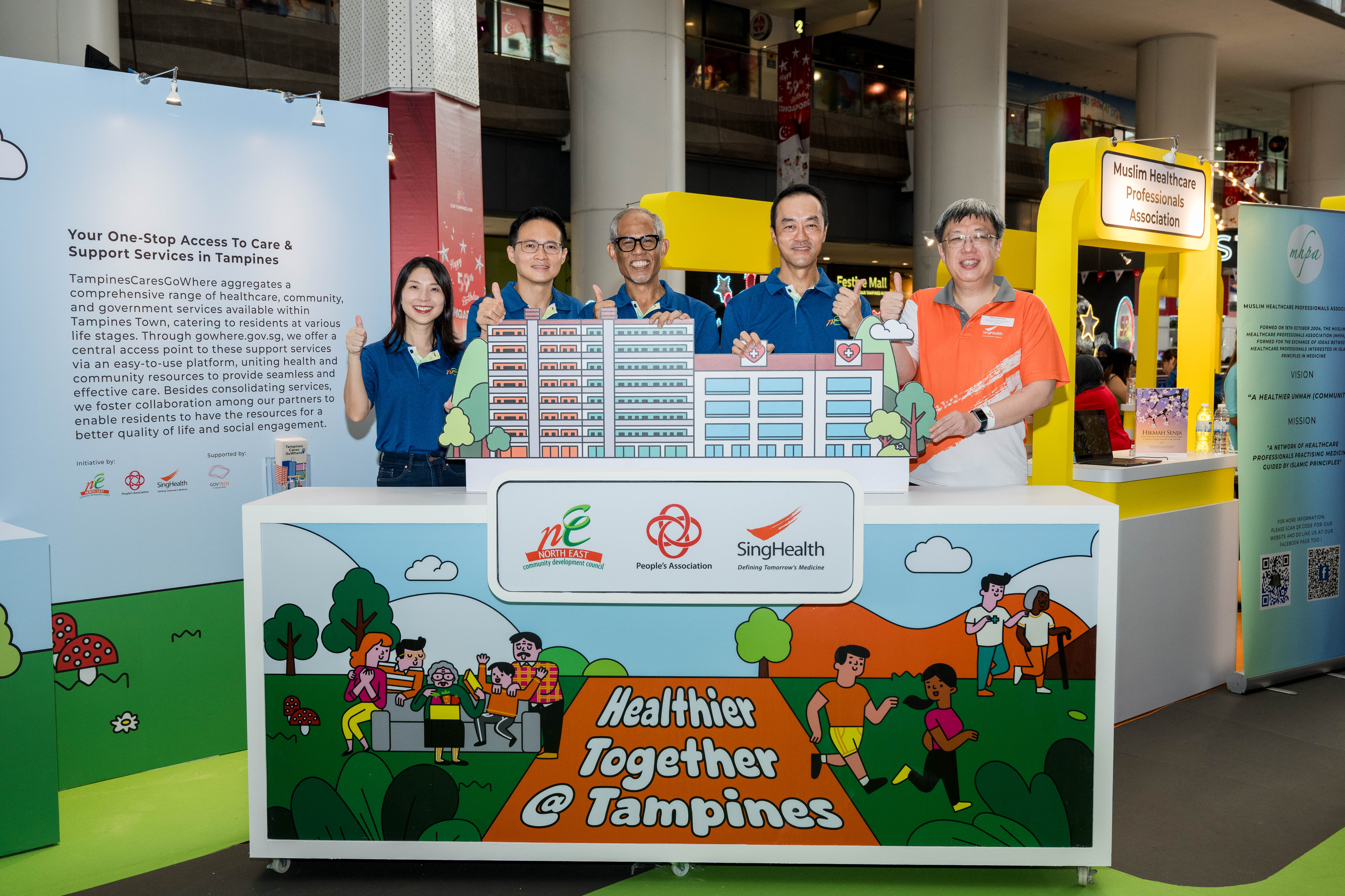 Community representatives gathered around a stand promoting Healthier Together @ Tampines posing for a photo.
